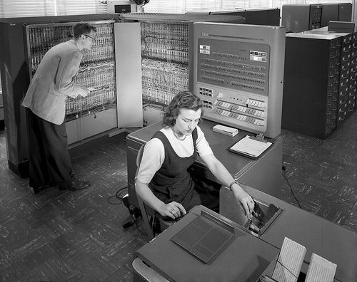 A woman operating an IBM mainframe computer in the mid-20th century.